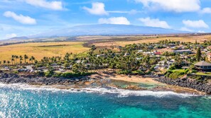 A coastal resort with beachfront properties, palm trees, and a view of distant mountains. - Kuau Plaza Paia Condo with Parking (Paia)