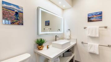 Une salle de bain moderne avec un lavabo blanc, un grand miroir et deux porte-serviettes fixés au mur.