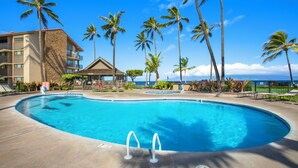 A swimming pool with palm trees and a building in the background.
