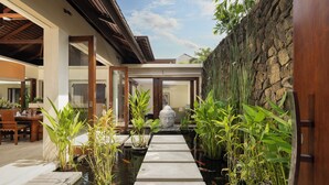A serene indoor garden with a koi pond, stone pathway, and lush greenery. - The Suar Seminyak by Nakula (Seminyak)