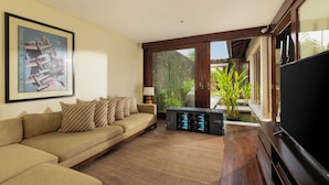 A living room with a sofa, a television, and a framed picture on the wall. - The Suar Seminyak by Nakula (Seminyak)