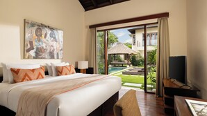 A hotel room with a large bed, a TV, and a view of a pool and garden. - The Suar Seminyak by Nakula (Seminyak)