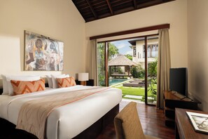 A hotel room with a large bed, a TV, and a view of a pool and garden. - The Suar Seminyak by Nakula (Seminyak)