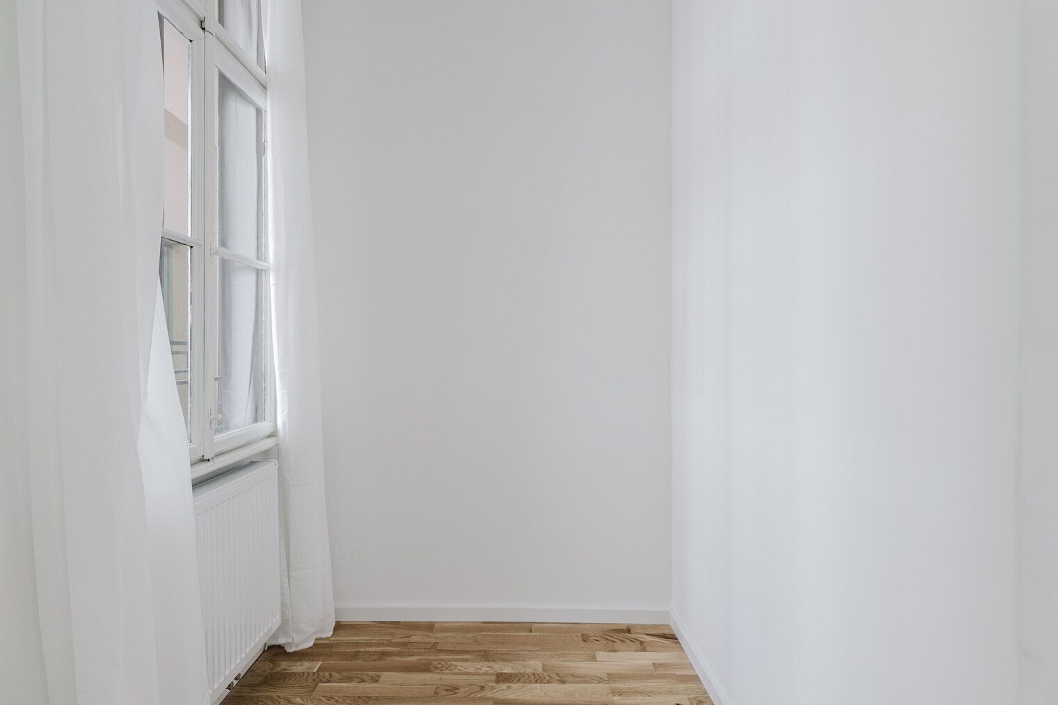 Un couloir étroit aux murs blancs et au plancher en bois.