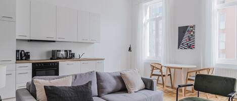 A modern living room with a grey sofa, a coffee table, and a dining area with a small table and chairs.