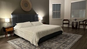 A bedroom with a large bed, a dark headboard, a patterned rug, and a wall-mounted decorative item. - Beautiful house in The Woodlands - Creekside (Tomball)