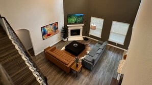 A modern living room with a fireplace, sofas, and a staircase. - Beautiful house in The Woodlands - Creekside (Tomball)