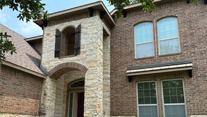 A two-story house with a stone facade, a central archway, and a brick section with large windows. - Beautiful house in The Woodlands - Creekside (Tomball)