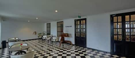 A hotel lobby with a checkered floor, a statue, and a reception desk.