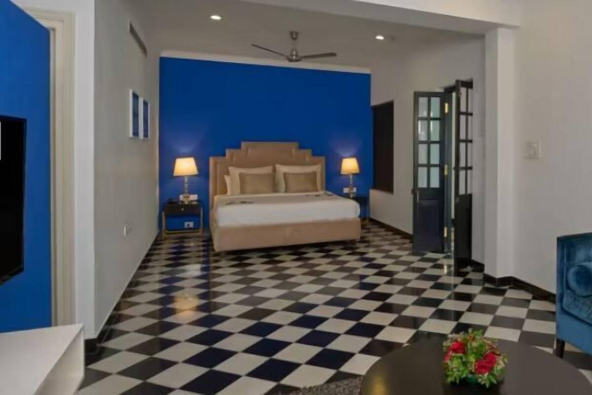 Ein Schlafzimmer mit kariertem Boden, einem Bett, einem blauen Sofa und einem kleinen Tisch mit Blumen.