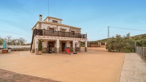 Una casa de dos pisos con un balcón, un aro de baloncesto y un tobogán en el jardín delantero.