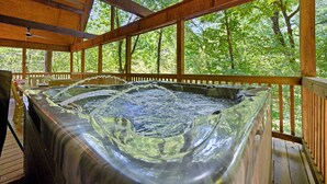 Un bain à remous situé sur une terrasse en bois, avec vue sur les arbres.