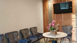 Una sala conferenze con un tavolo rotondo, quattro sedie, una TV a parete e un centrotavola floreale.