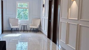 A hallway with two chairs, a small table, and a door. - D'Ninety Six Inn (Playen)