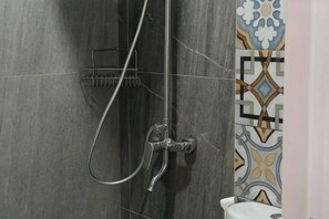 A shower area with a handheld showerhead, a wall-mounted faucet, and a towel rack. - D'Ninety Six Inn (Playen)