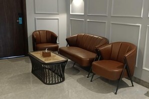 A room with a brown leather sofa set, a coffee table, and a door in the background.