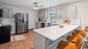 A modern kitchen with a large island, stainless steel appliances, and a ceiling fan. - Hot Tub - Game Room - Sleeps 10 - Vermilion (Vermilion)