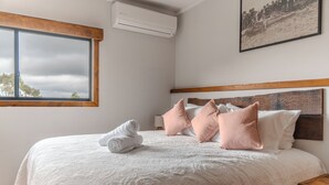 A neatly made bed with a white duvet, pink pillows, and rolled towels. - Mount Mee Country Lodge (Mount Mee)
