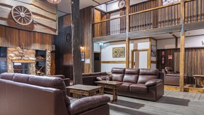 A spacious lounge area with leather sofas, a stone fireplace, and wooden accents. - Mount Mee Country Lodge (Mount Mee)