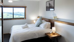 A neatly made bed with white linens, a wooden headboard, and two bedside lamps. - Mount Mee Country Lodge (Mount Mee)