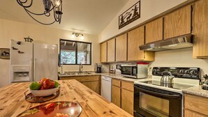 A kitchen with wooden cabinets, a stainless steel range hood, a microwave, a stove, and a refrigerator. - Bobcat Bungalow - Quaint, Quiet & Cozy Retreat in Munds Park - Yes, there's A/C! (Munds Park)