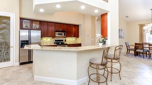 Une cuisine moderne dotée d’un îlot central, d’appareils électroménagers en acier inoxydable et de meubles de rangement en bois.