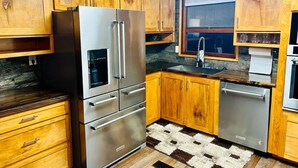Una cocina con armarios de madera, electrodomésticos de acero inoxidable y un tapete a cuadros.