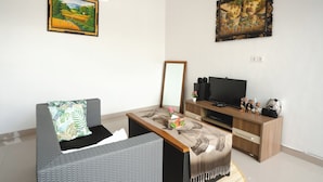 A living room with a sofa, a coffee table, a TV, and two paintings on the wall.