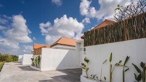 A residential area with white walls, a bamboo fence, and a tiled roof.