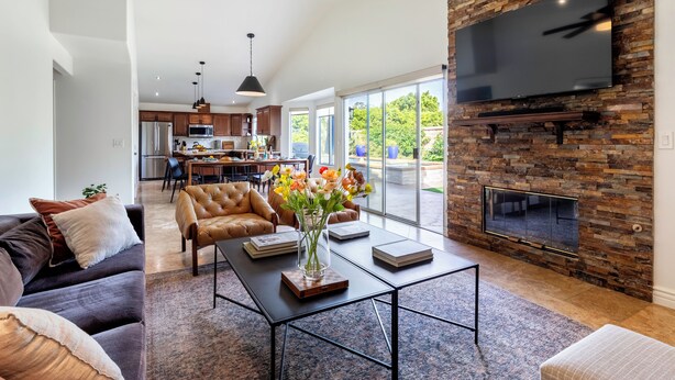A modern living room with a fireplace, a television, and a dining area in the background.