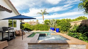 A backyard with a swimming pool, a barbecue grill, and outdoor furniture.