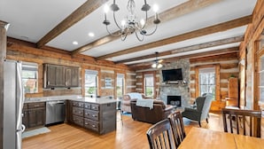 Un intérieur spacieux de chalet en bois, comprenant une cuisine, un coin repas et un salon.