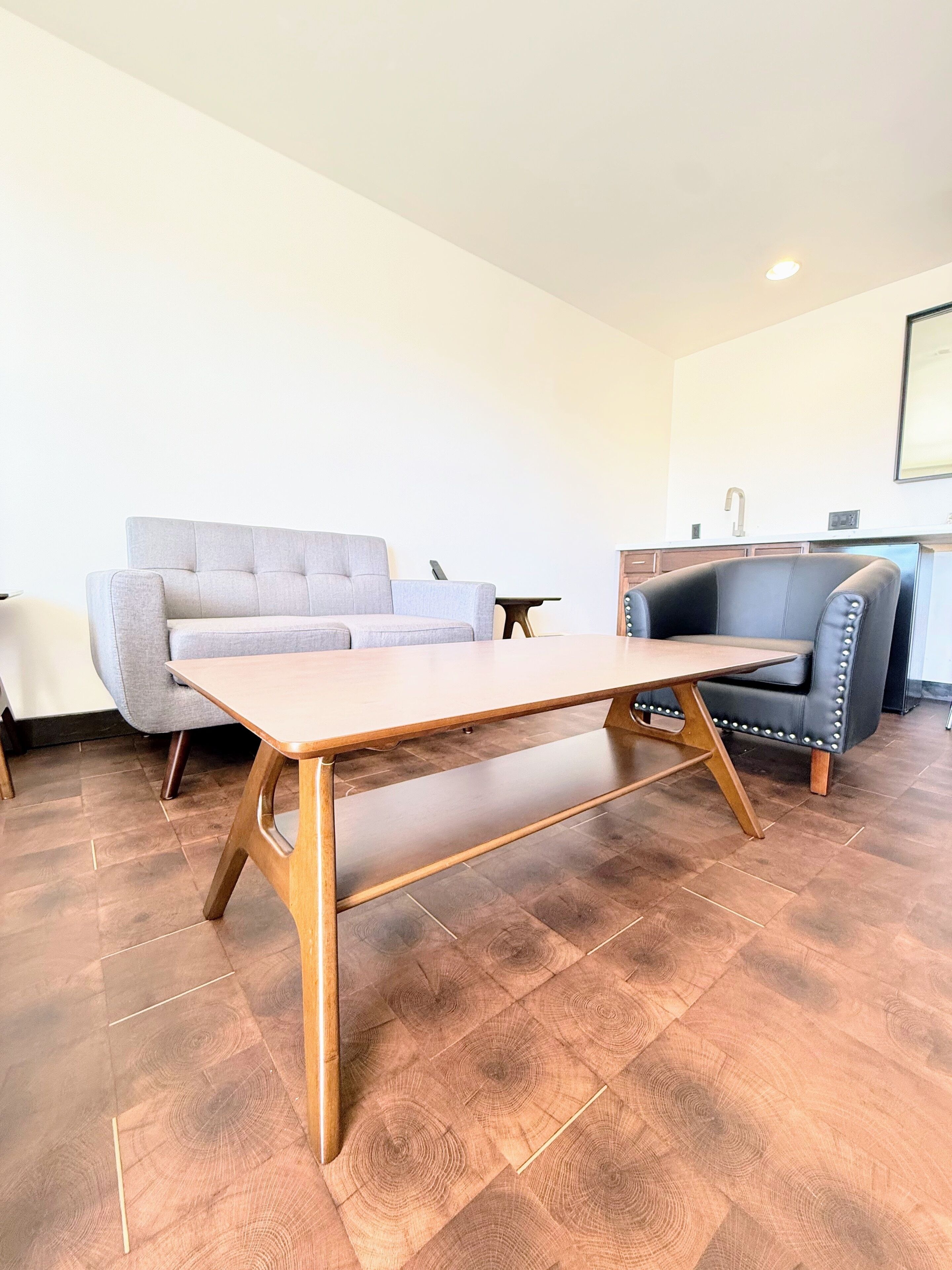 A living room with a wooden coffee table, grey sofa, and a black leather chair.