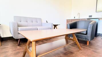 A living room with a wooden coffee table, grey sofa, and a black leather chair.