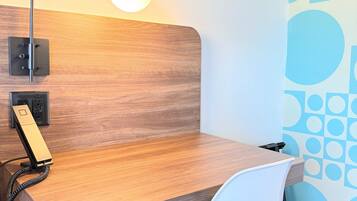 A wooden desk with a white chair, a desk lamp, and a telephone.