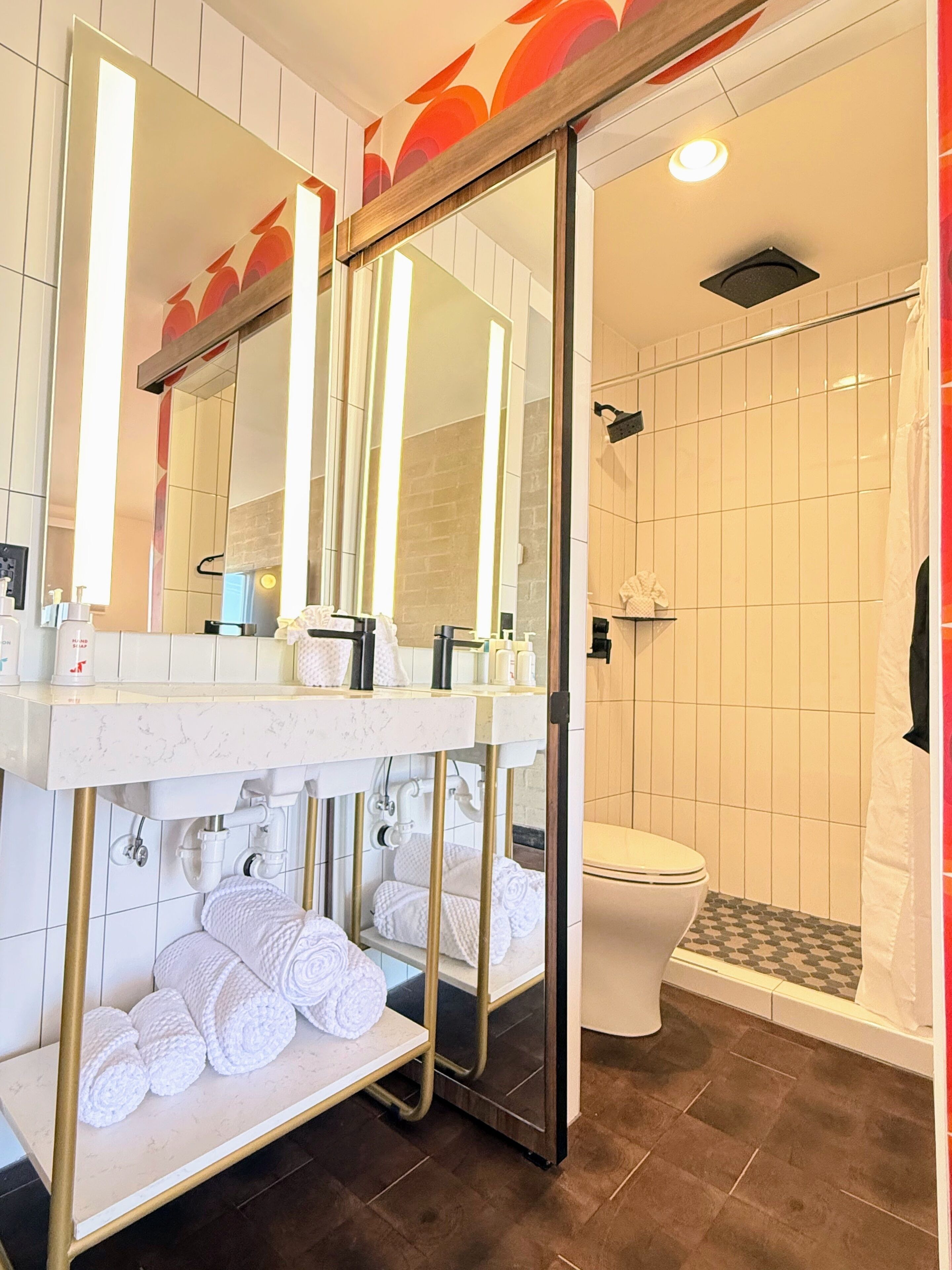 A modern bathroom with a marble vanity, a large mirror, a toilet, and a shower area.