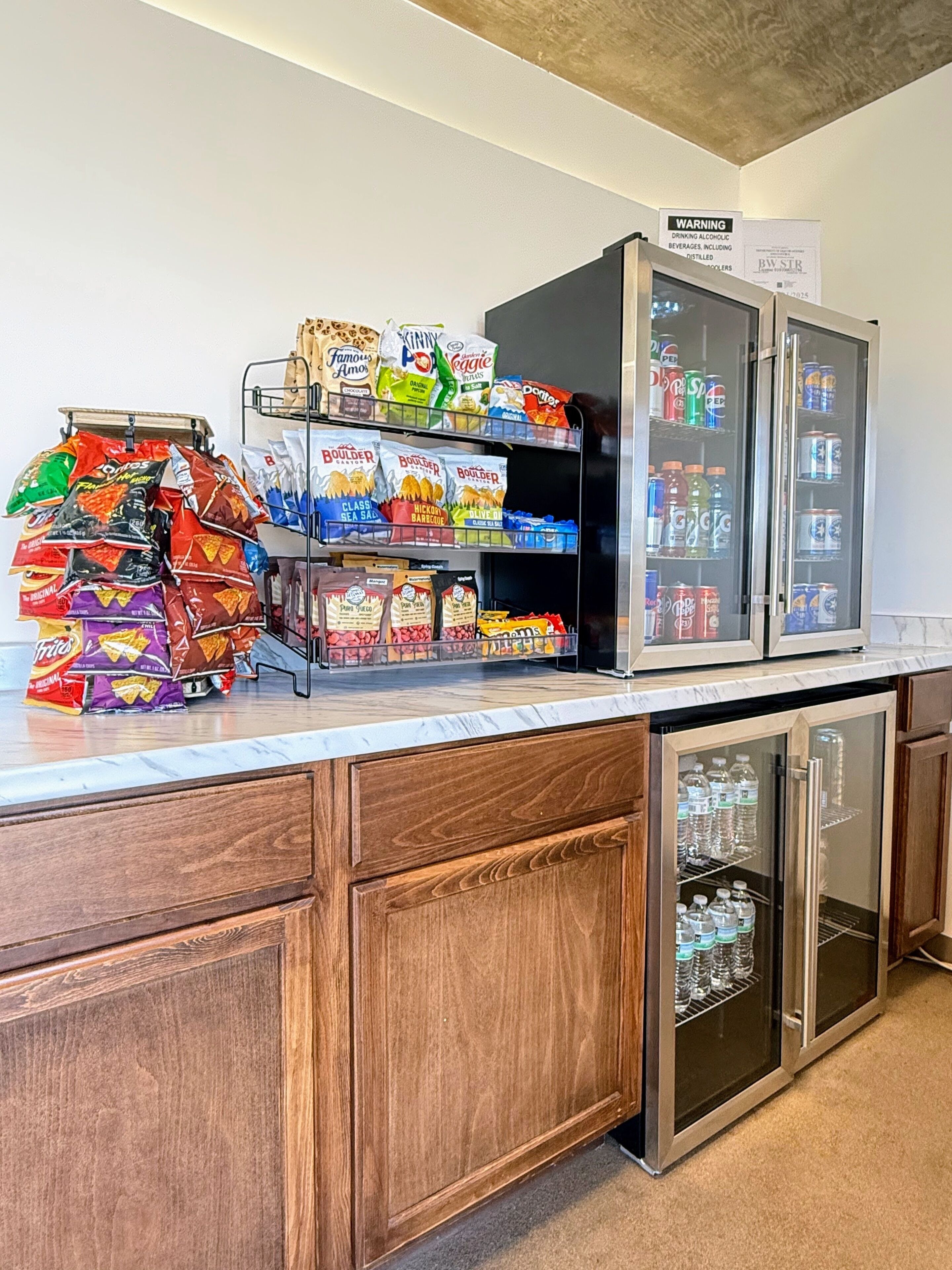 A snack and beverage station with various chips and bottled drinks.