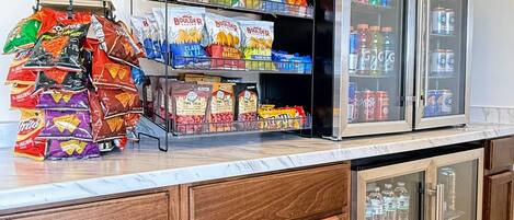 A snack and beverage station with various chips and bottled drinks.