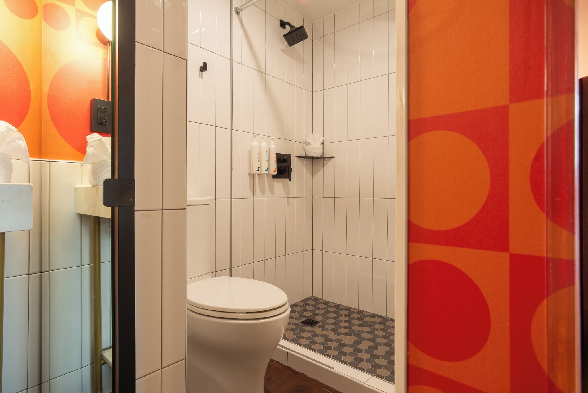 Une salle de bain avec des toilettes, une douche et des murs carrelés.