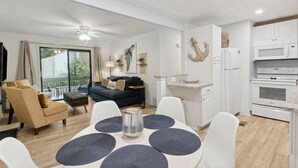 Een moderne woonkamer met een bank, eettafel en keukenhoek.