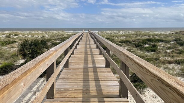 Een houten looppad naar het strand.
