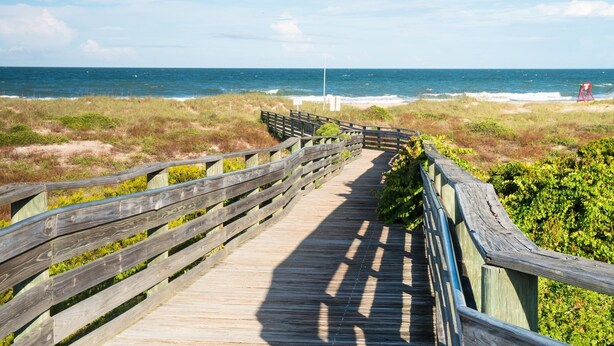A wooden boardwalk leading to the beach with a red lifeguard chair visible in the distance. - American Beach Retreat - Hosted by Moore AI Rentals (Fernandina Beach)