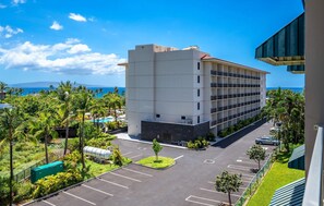A multi-story hotel with a parking lot and a view of the ocean.