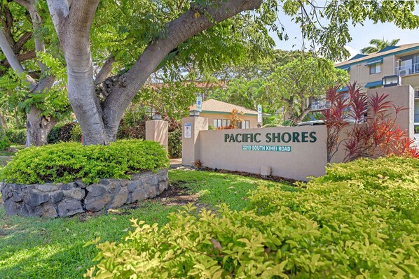 Señal de Pacific Shores, con un muro de piedra y follaje al frente.