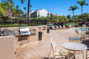 Un espace extérieur avec une piscine, des chaises longues, un barbecue et une poubelle.