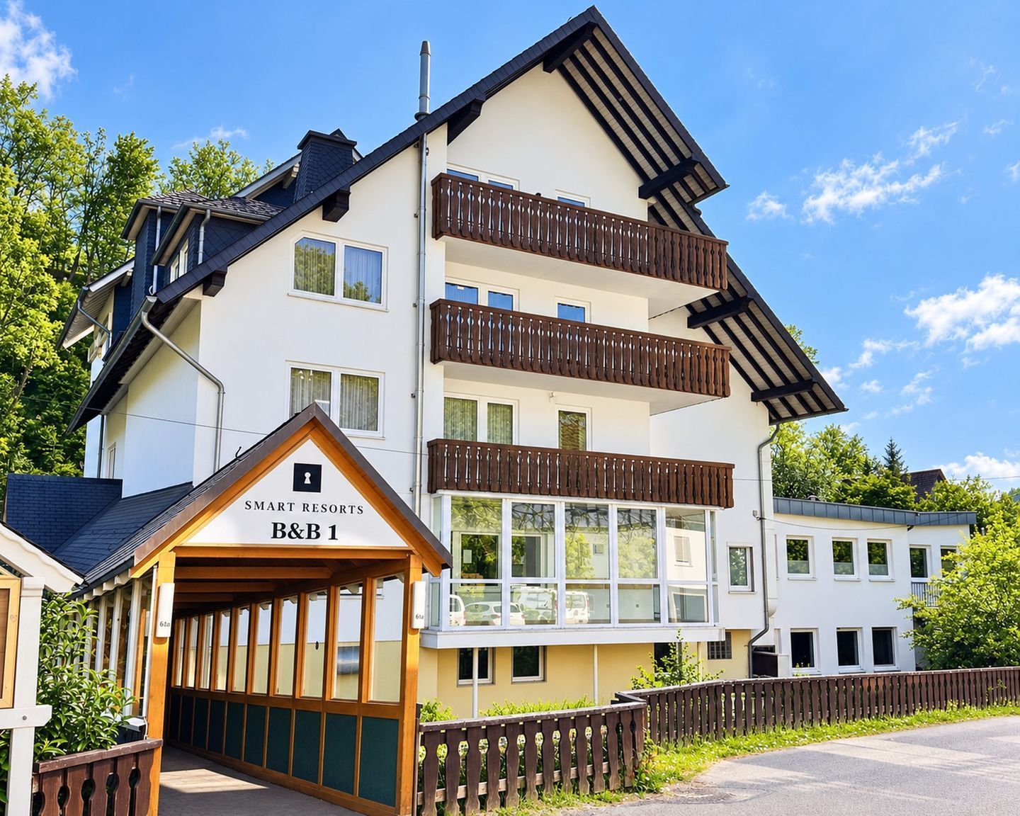 Een hotel met meerdere verdiepingen, balkons en een bordje met de tekst 'SMART RESORTS B&B 1'.