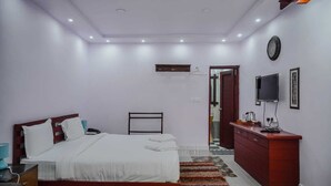 A bedroom with a bed, bedside table, TV, and a wardrobe. - Green Point Hotels and Resorts (Angul)