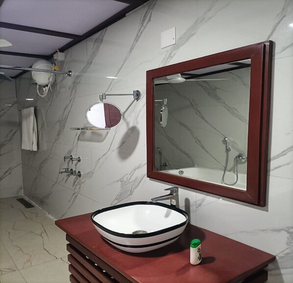 A bathroom with a marble wall, a large mirror, a white sink, and a red vanity. - Green Point Hotels and Resorts (Angul)