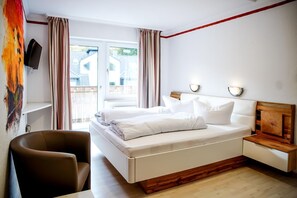 Ein Schlafzimmer mit einem Bett, Nachttischen, einem Sessel, einem Fernseher und einem Fenster mit Vorhängen.