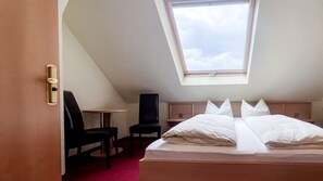 A room with a bed, a desk, a chair, and a skylight.